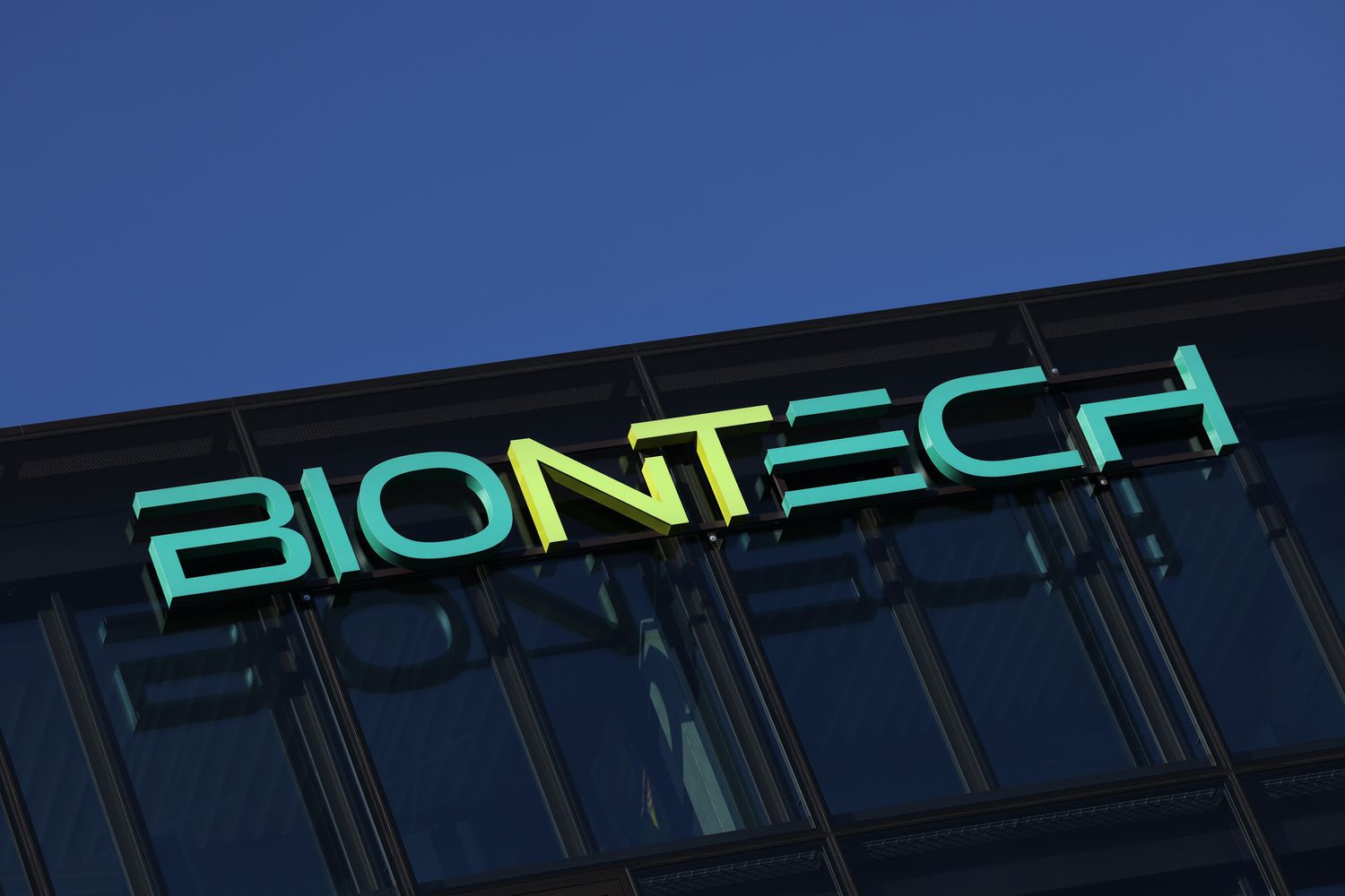 The green BioNTech logo is seen on the side of a black office building.