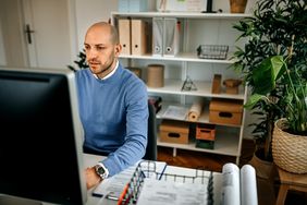 Man in sitting at a desk looking at computer.