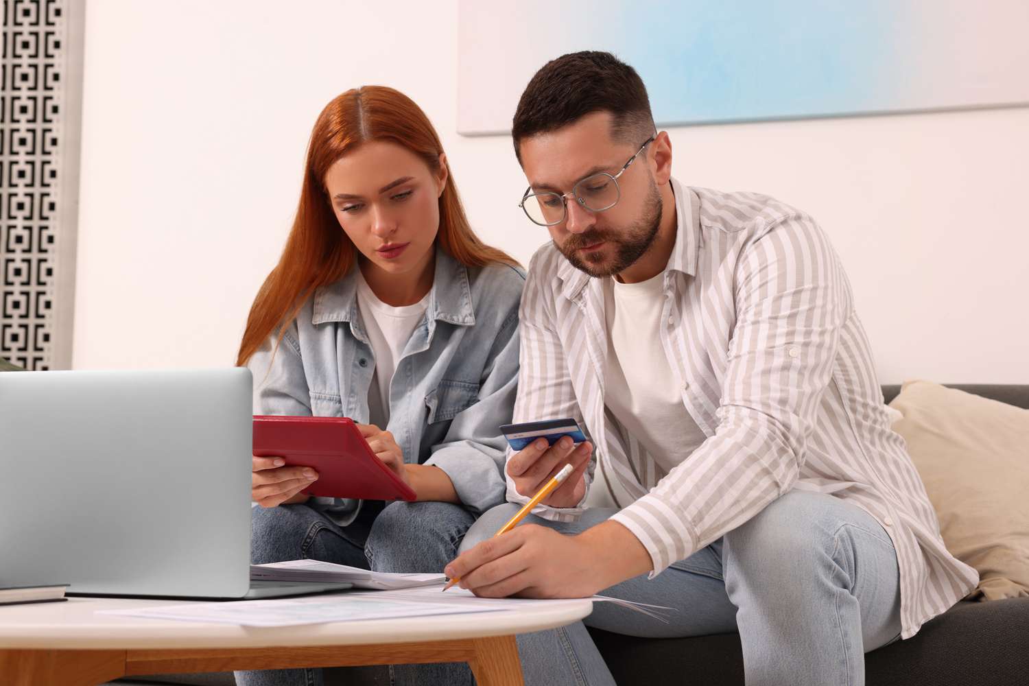 Young couple sitting on their sofa and calculating possible mortgage payments