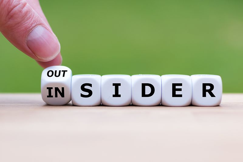 Hand turns a dice and changes the word 'OUTSIDER' to 'INSIDER' (or vice versa).