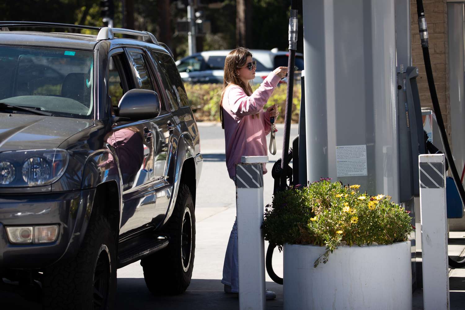 A woman gets gasoline for her car at a gas station