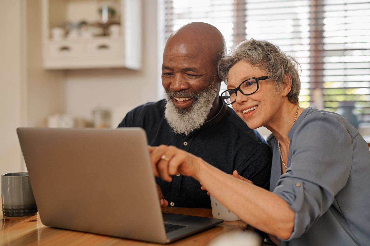 Older couple at their kitchen table, looking at mortgage rates on a laptop