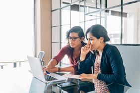 Two women discussing something on a laptop
