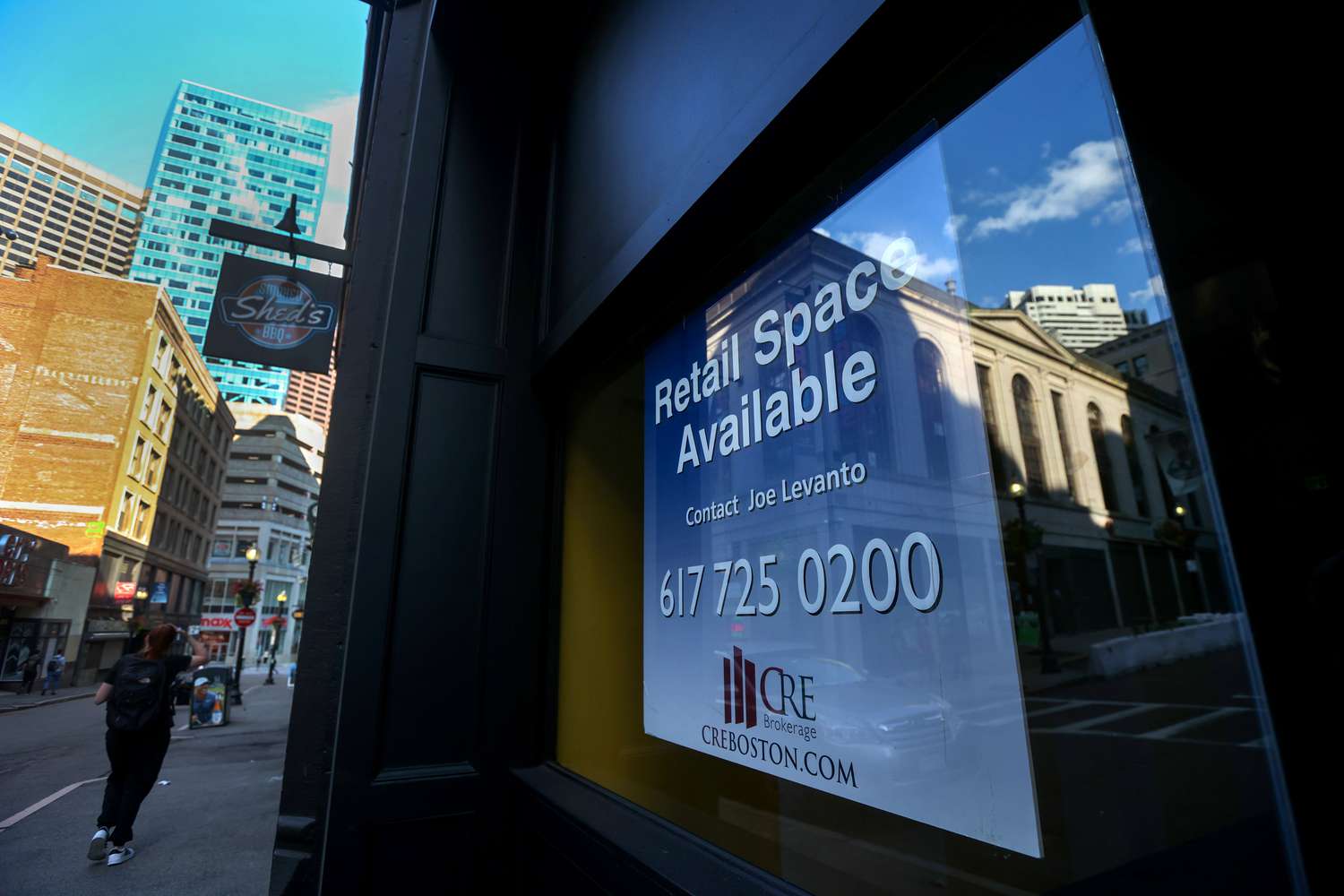 A sign in a store window advertises retail space available to lease. 