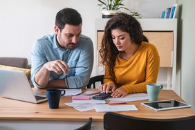 A couple reviews paperwork at a desk.