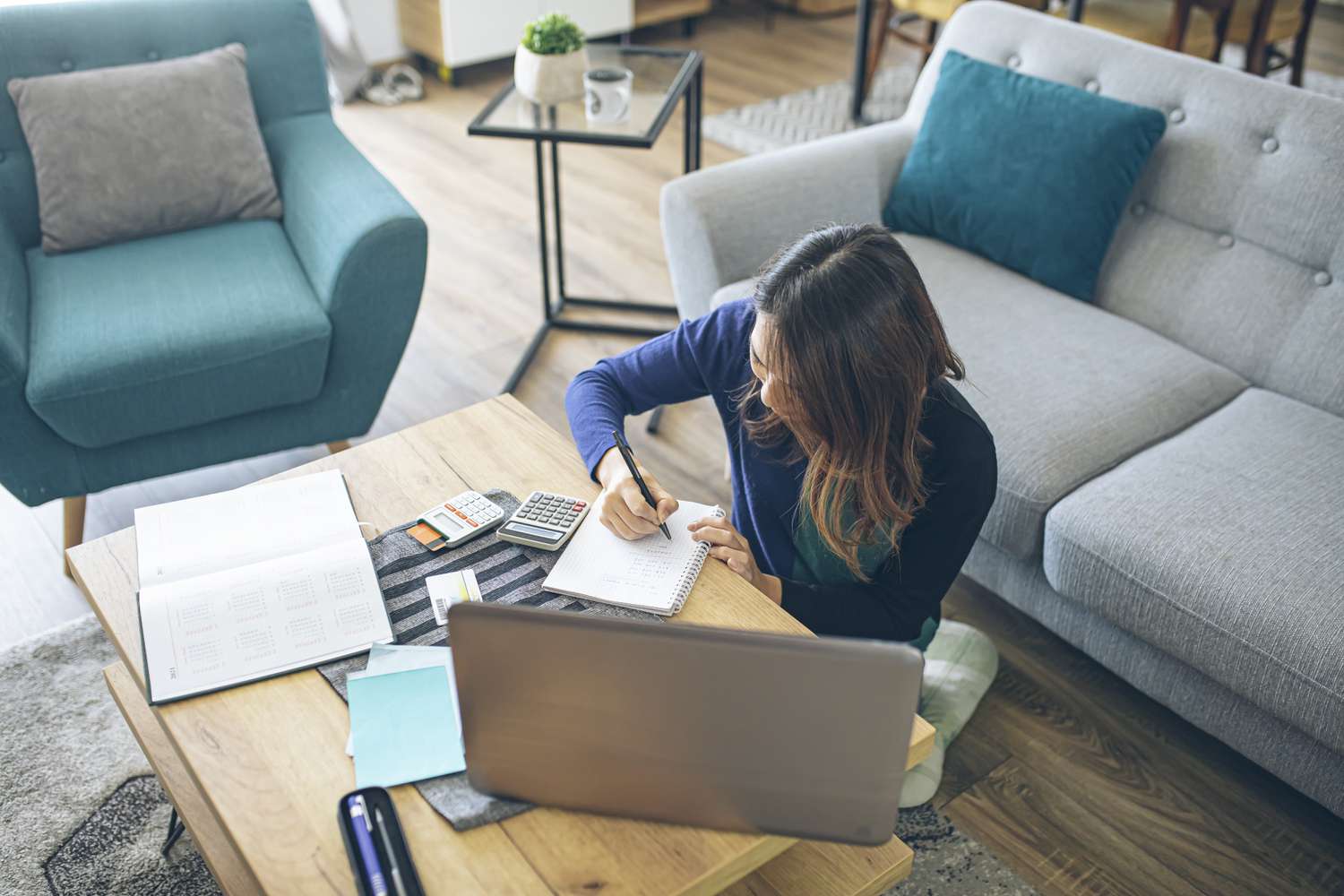 Woman notes down bills and makes calculation while sits on the floor in the living room to determine the ability to repay debts.