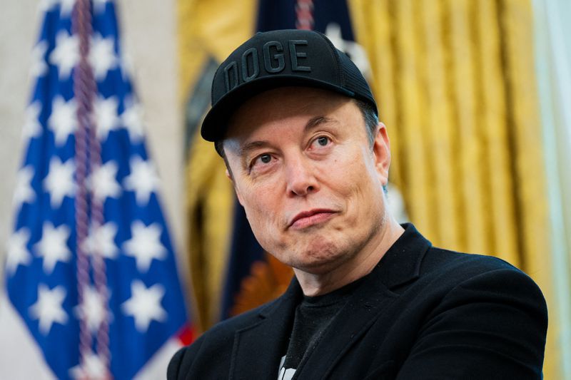 Elon Musk, wearing a black "DOGE" cap