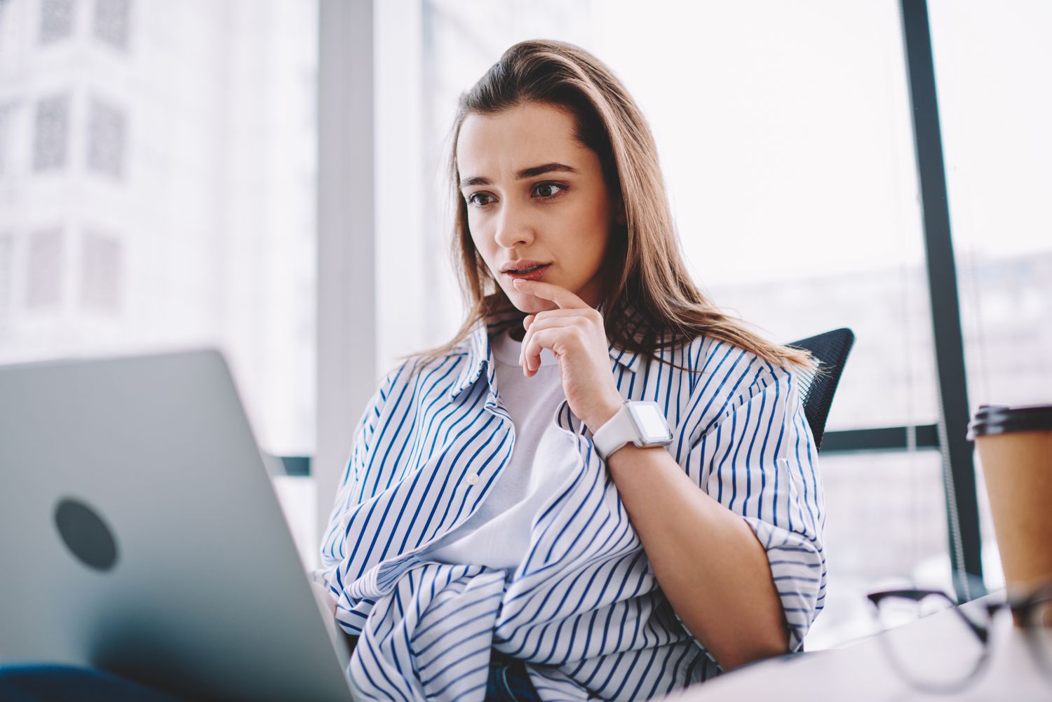 Woman in her 20s or 30s looking intently at something on her laptop