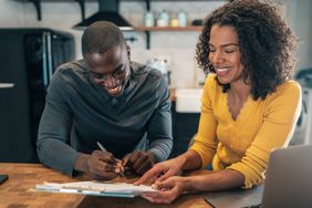 Male signing an important document on a clipboard female is holding