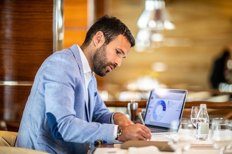 An entrepreneur writing on a document while sitting in a restaurant.