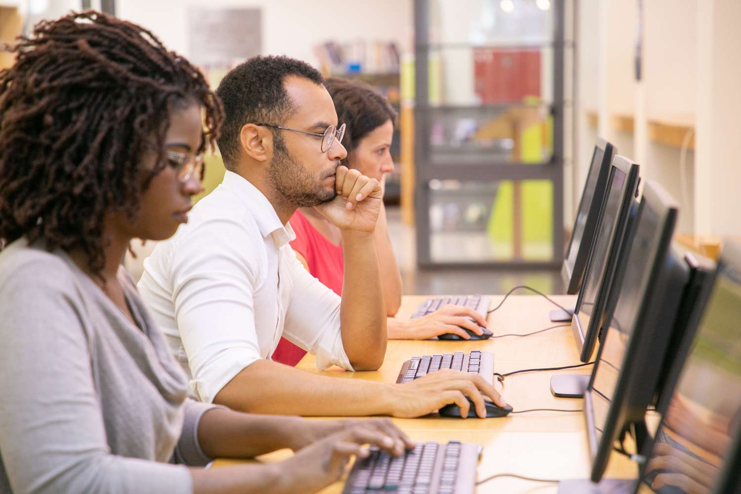 A row of financial advisors take the FINRA Series 4 exam at a testing center using computers.