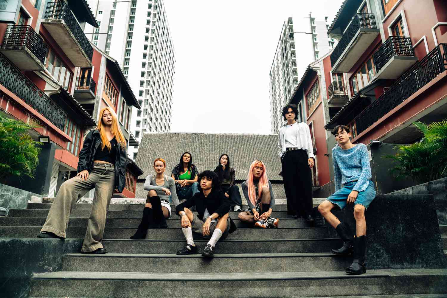 Group of young adults posing confidently on city steps in trendy streetwear.