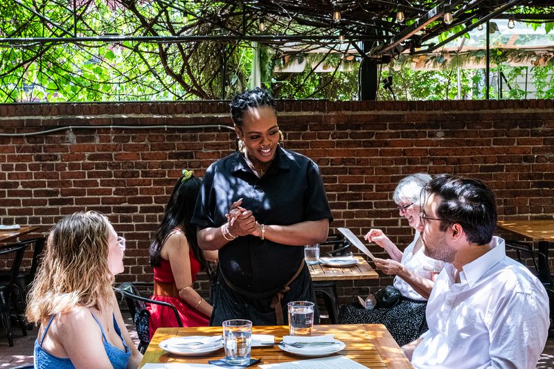 Waitress Amber Keys talks with Ella Lane and Justin Becker Gold at Iron Gate in Washington, DC on May 3, 2025.