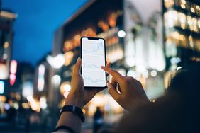 Businesswoman reading financial trading data on smartphone
