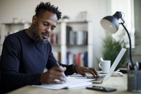 A man researched the best high-yield business savings accounts, sitting a desk with some paperwork.