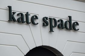 The black Kate Spade logo is seen on the side of a white building.