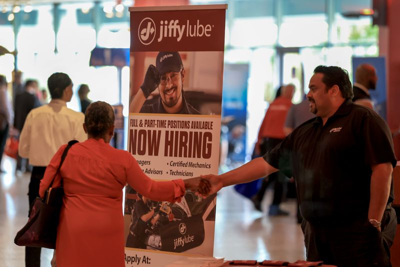 Job fair with a Jiffy Lube recruitment banner, two individuals interacting in front of it