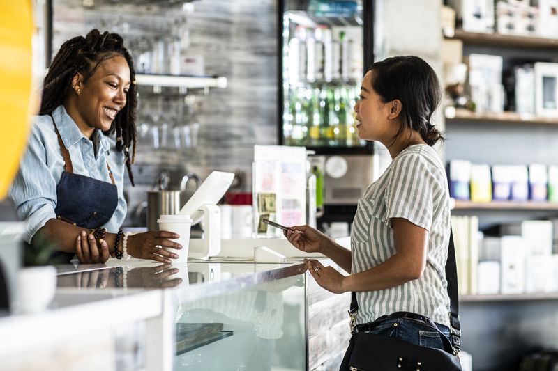 A woman buys coffee with a credit card.