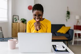 Young woman sitting in front of laptop and is excited about what she is reading or seeing.