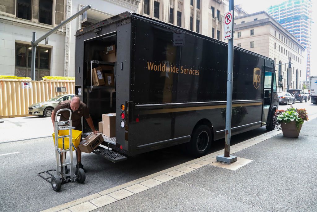 A UPS driver retrieves packages from the back of his truck.