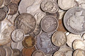 A close-up of a collection of antique silver coins lay spread out on a surface