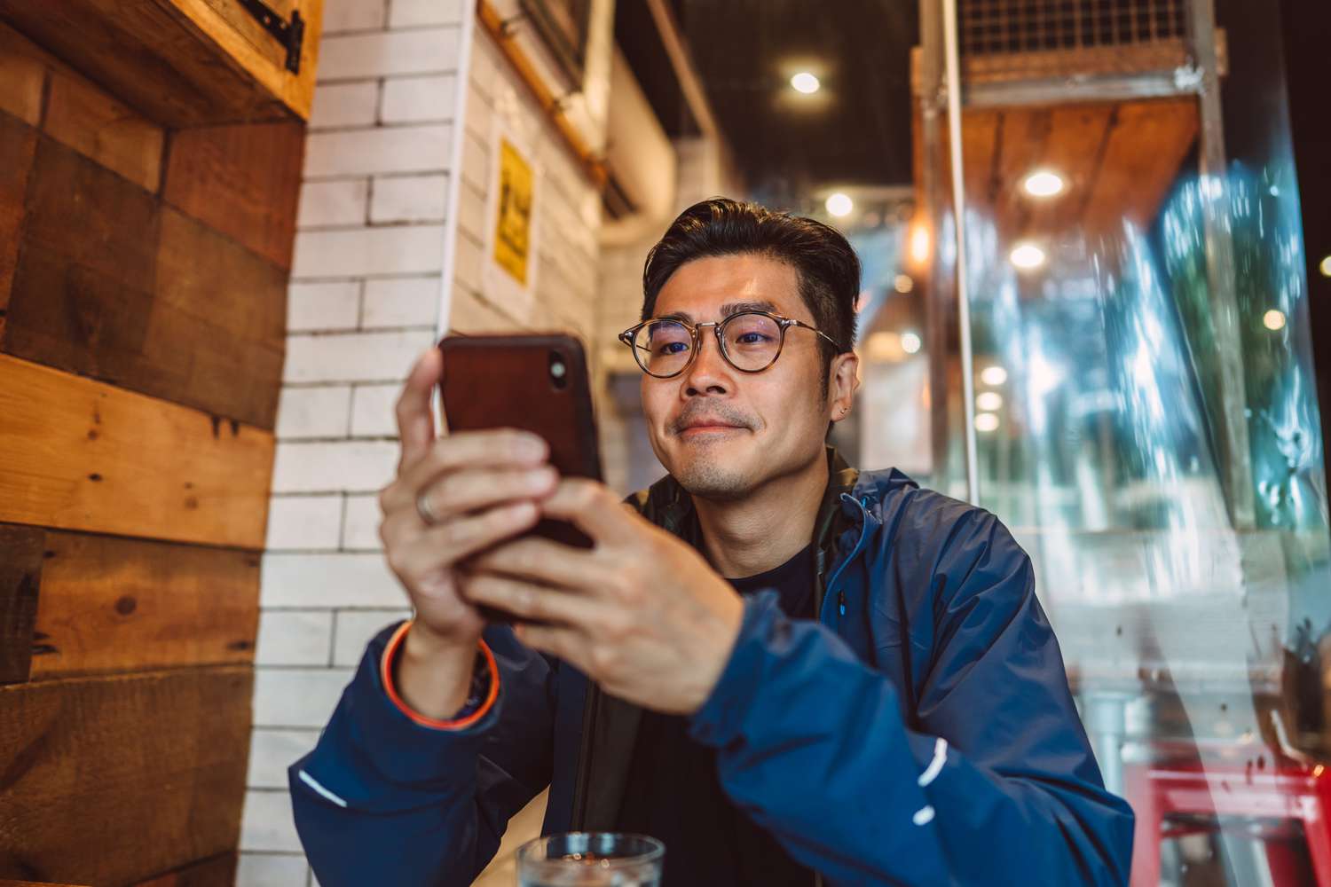 A young man looks at his phone in a restaurant.