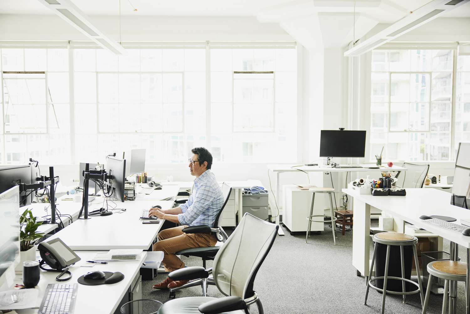 Wide shot of businessman working on computer at workstation in empty office