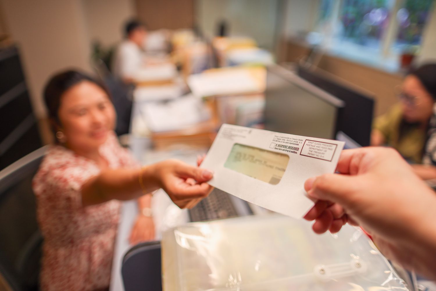 Someone handing a woman an IRS check sealed in an envelope. 