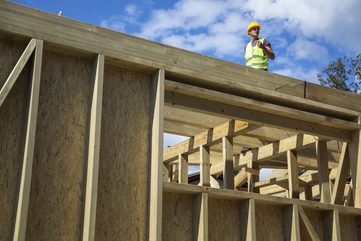 A construction worker stands atop a new home under construction.
