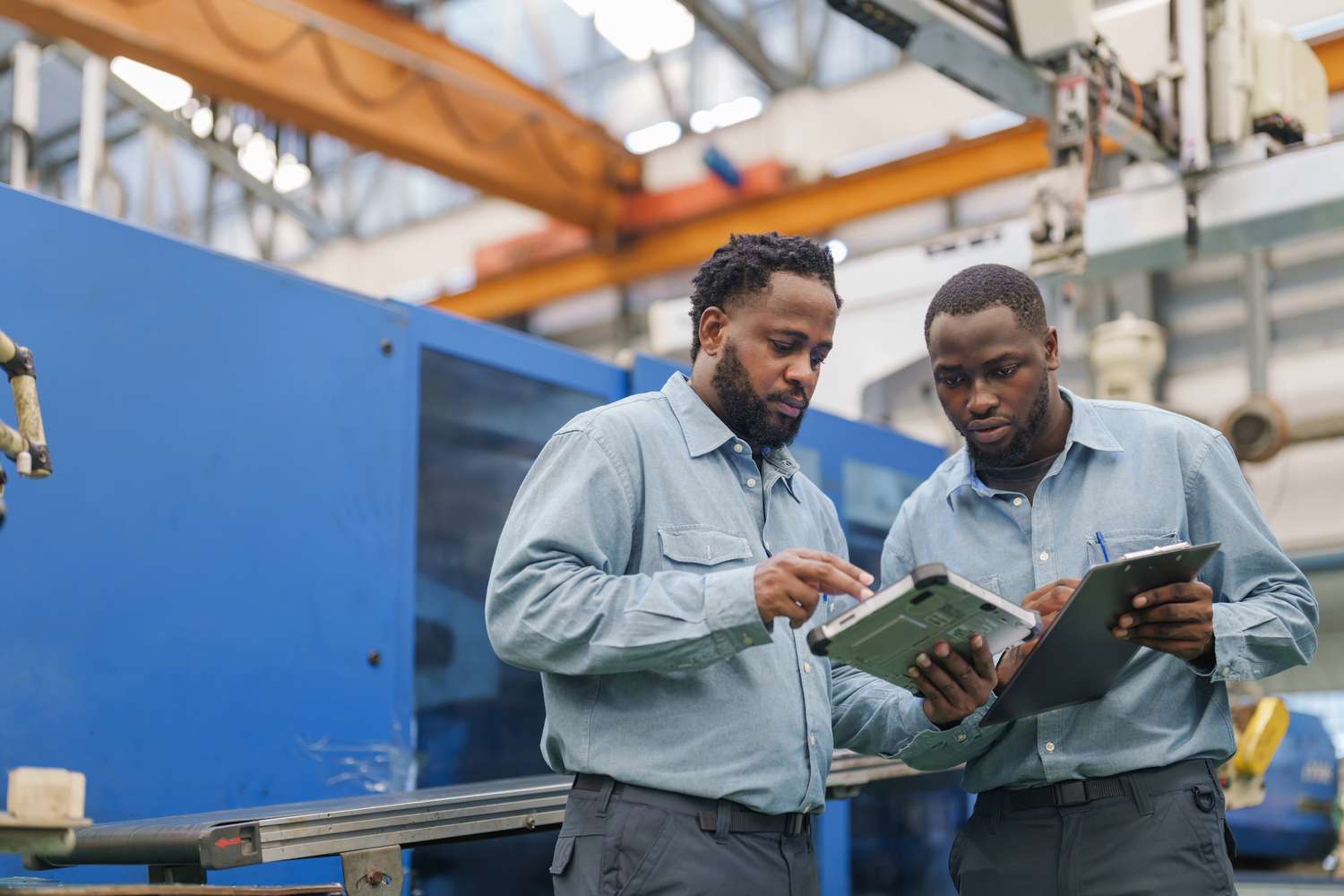 Senior engineer explaining machine functioning to new engineer and how to operating an Injection Molding machine. 