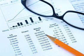 A pencil over a financial document with eyeglasses.