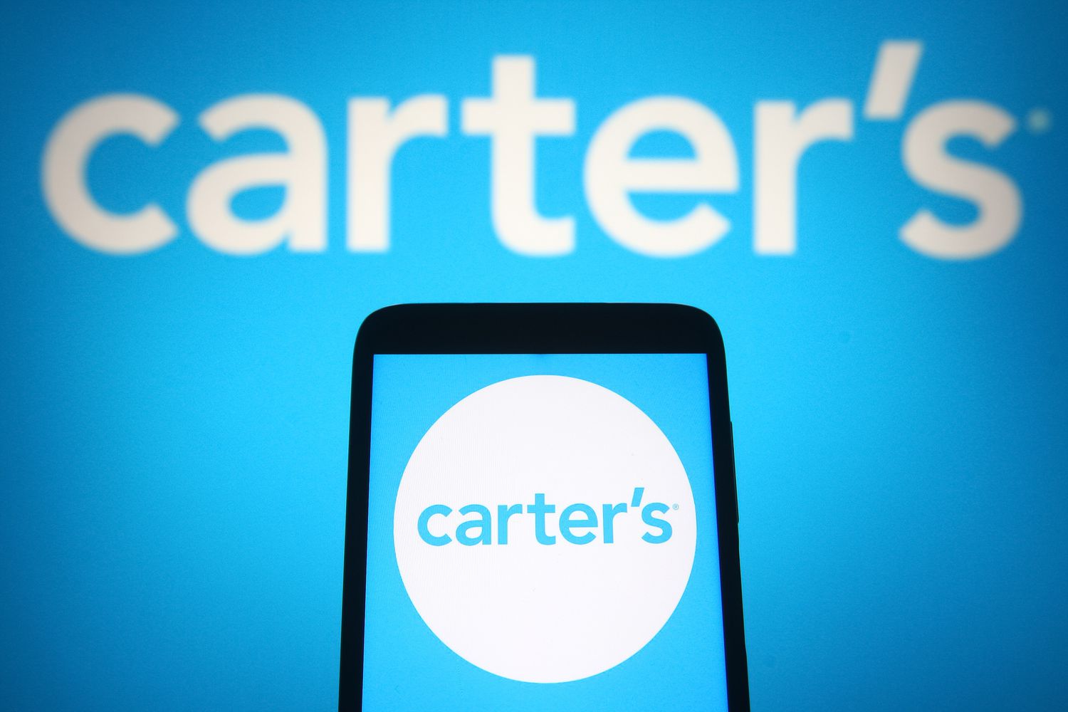 The blue and white Carter's logo is seen on a phone screen, with a larger version of the logo in the background.