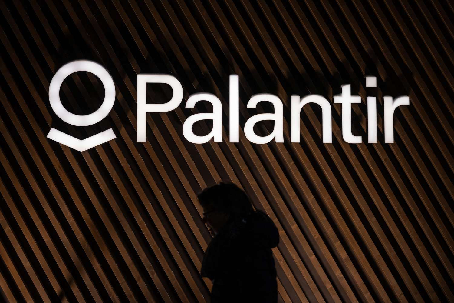 A person walks by a Palantir logo.