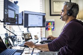A person watching two screens with headset on.