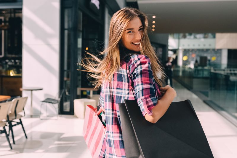 Happy woman with multiple shopping bags as she looks over her shoulder.
