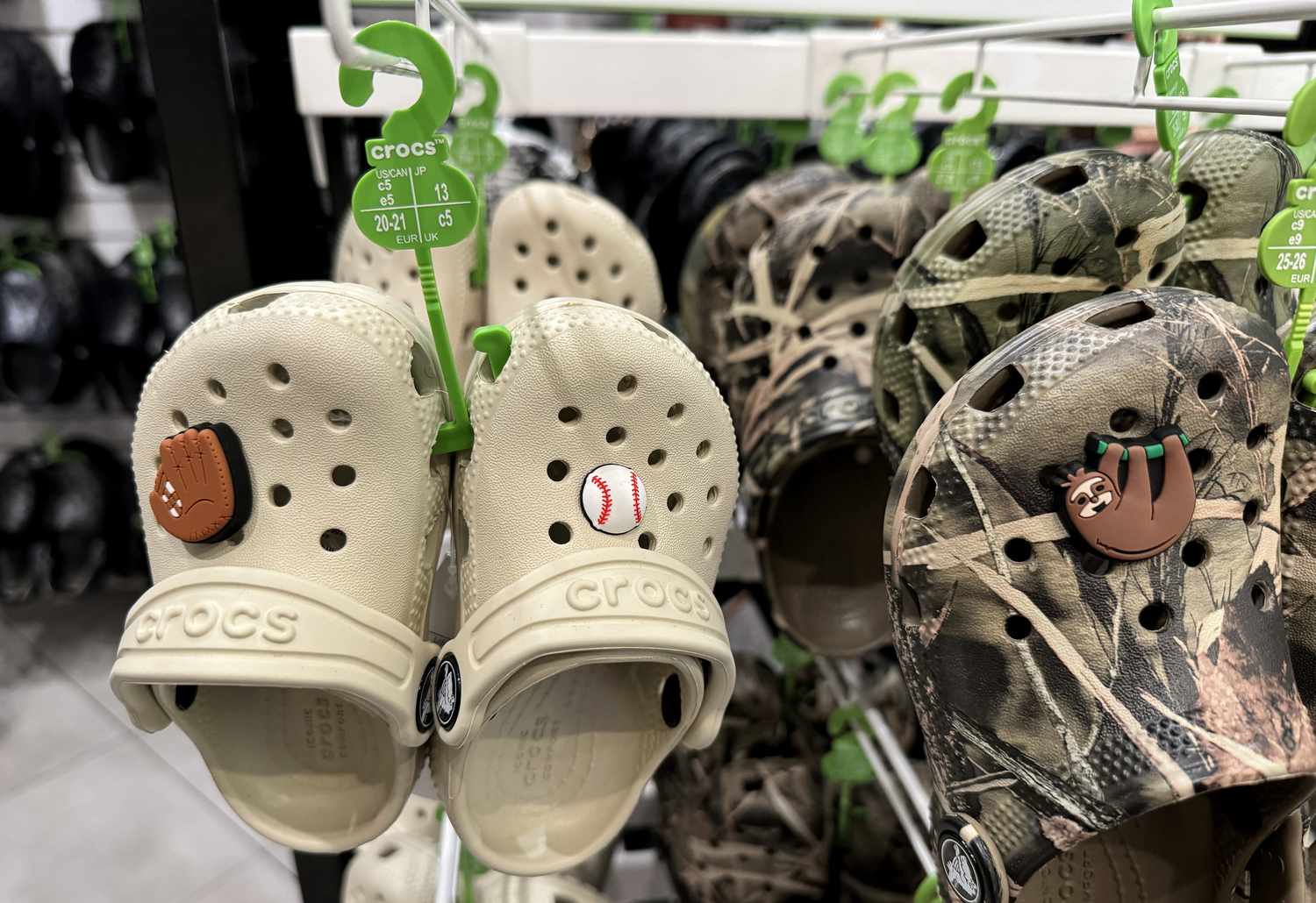 Tan and camo Crocs hang in a store