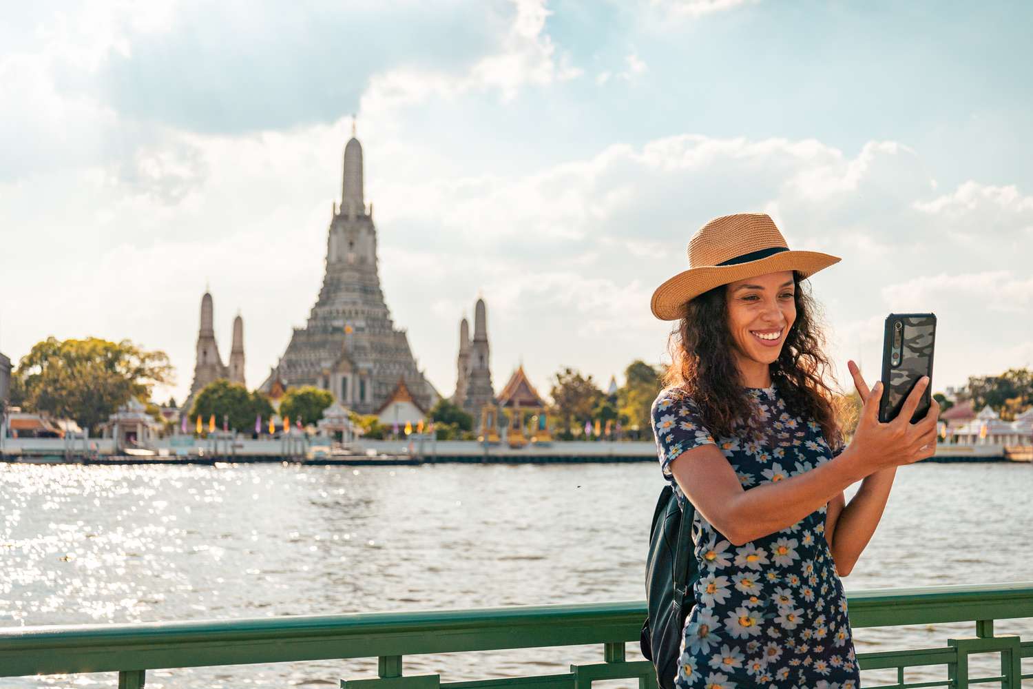 Woman smiling into phone in front of temple in Bangkok
