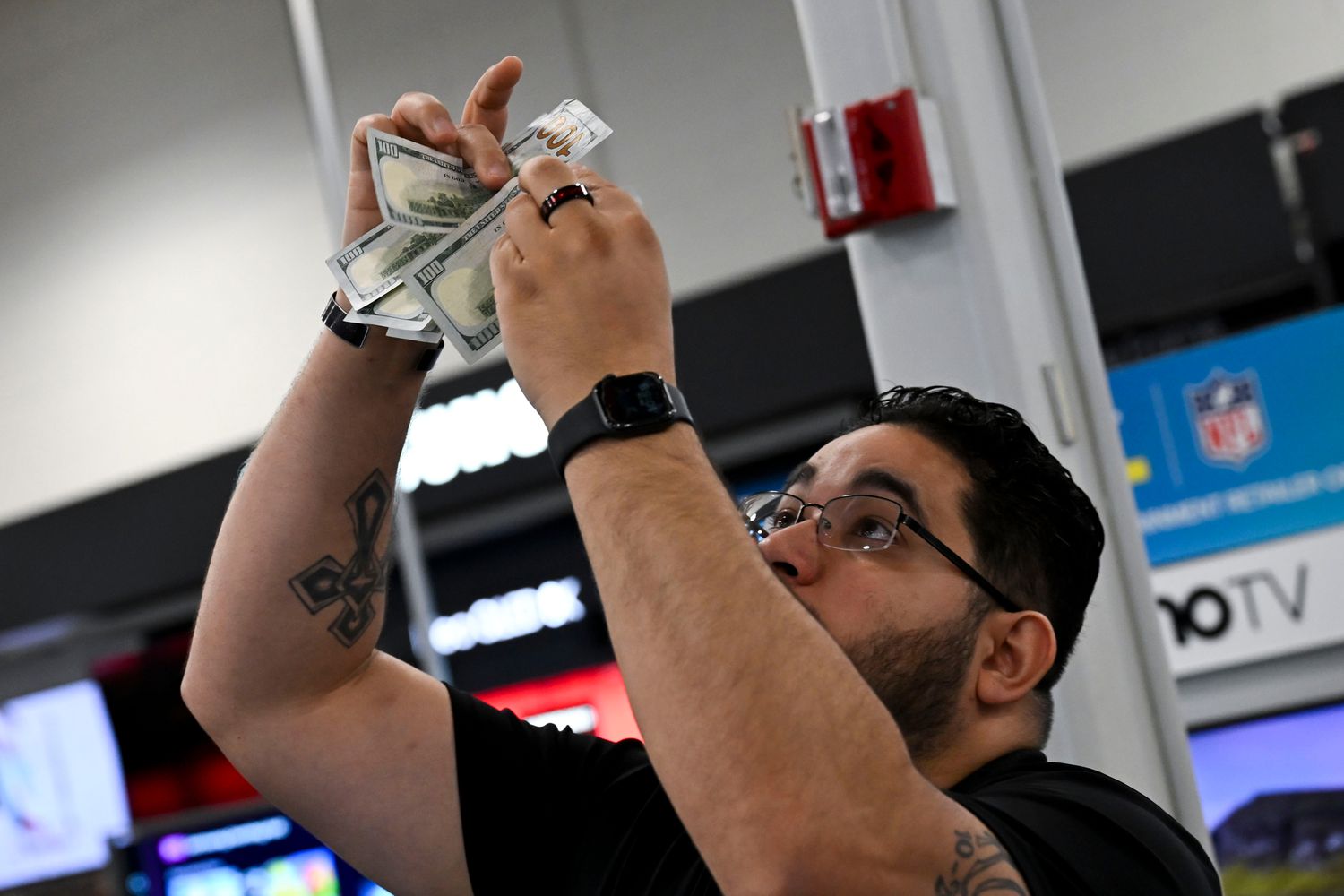 A Best Buy employee checks the legitimacy of 100-dollar U.S. banknotes at the company's store
