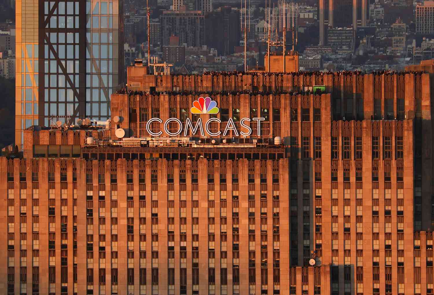 The sun sets on the Comcast corporate logo at the top of 30 Rock as people visit the Top of the Rock observation deck seen from the Empire State Building on November 2, 2023, in New York City