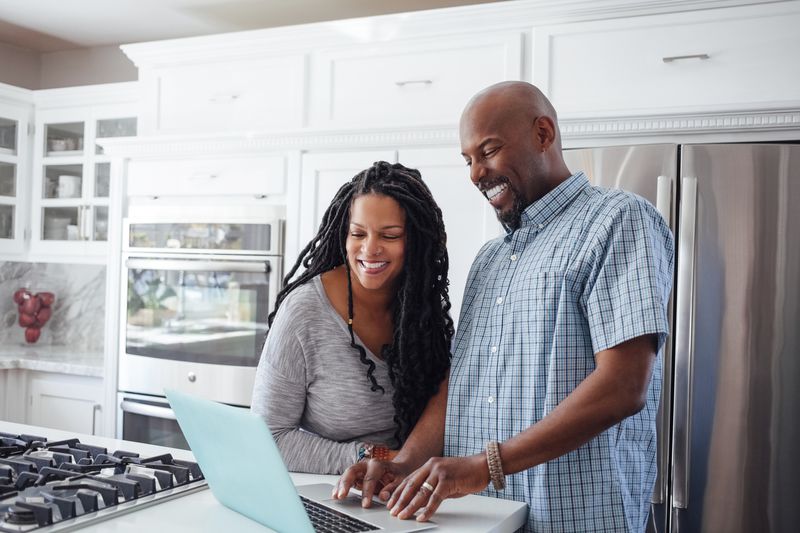 A couple working on a laptop on their kitchen counter