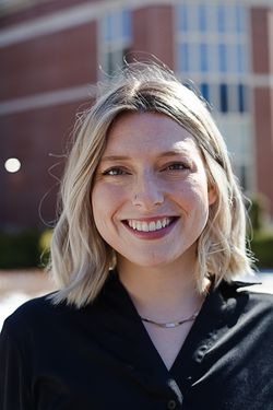 A woman with short blonde hair smiles for a headshot. 