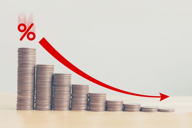 Coin stacks stepping down graph with red arrow and percent icon.