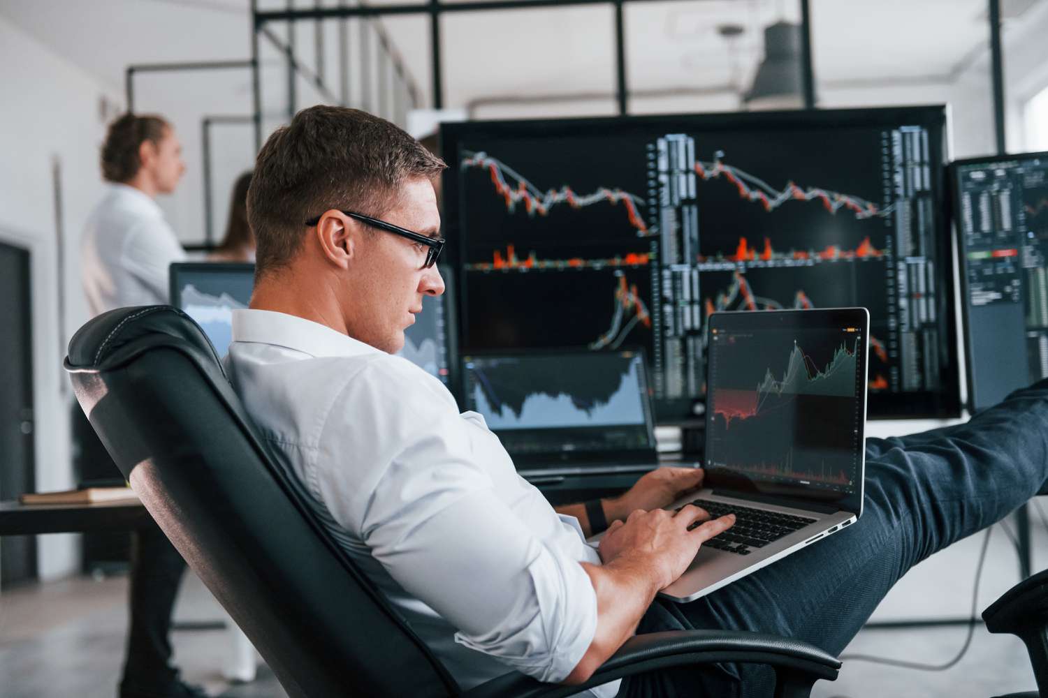 A stock trader focusing on their laptop for trade signals at work