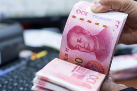 A person counting a stack of Chinese yuan bank notes.