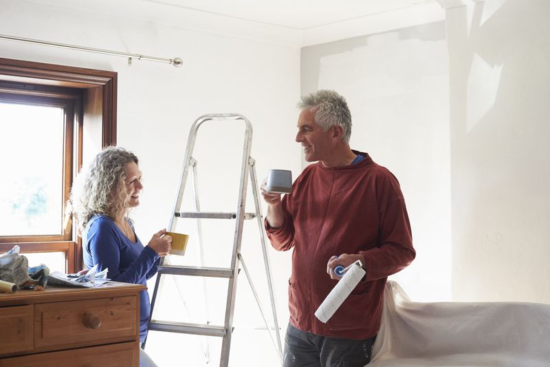 A couple takes a coffee break from painting a room in their home.
