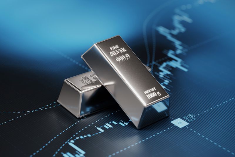 Silver bullion bars lay on a graph showing the change in value of funds investment in silver assets.