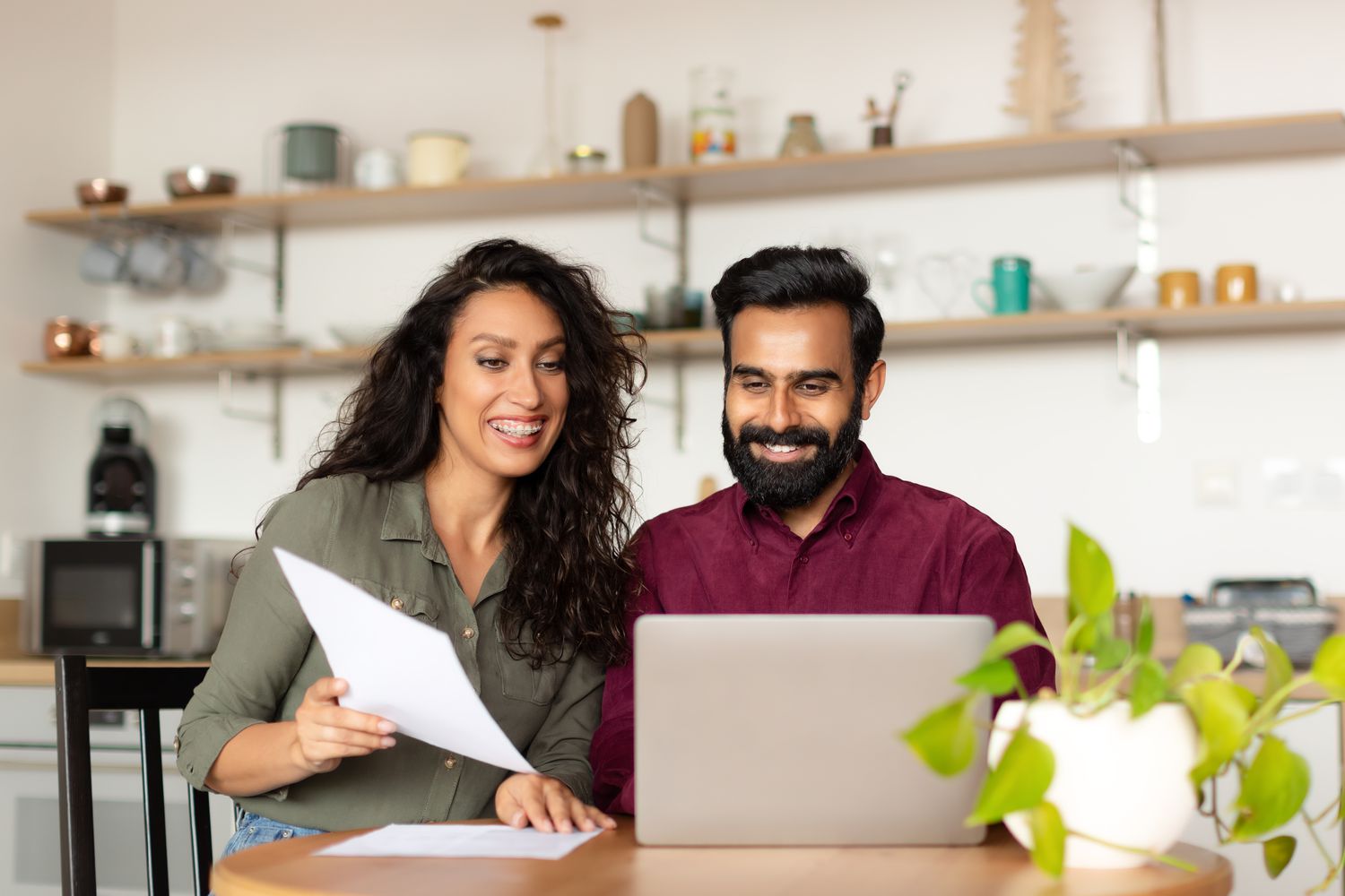 A couple in a kitchen with papers and a laptop