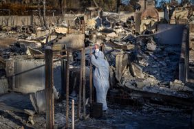 Wearing protective gear, Eaton fire victim Liz Oh, is overwhelmed with emotion as she pauses from searching for keepsakes and valuables with her husband Ray Ahn, not pictured, amid the rubble of their burned out home of six years on W. Marigold Street, as residents return to their burned out homes in Altadena Tuesday, Jan. 21, 2025. 