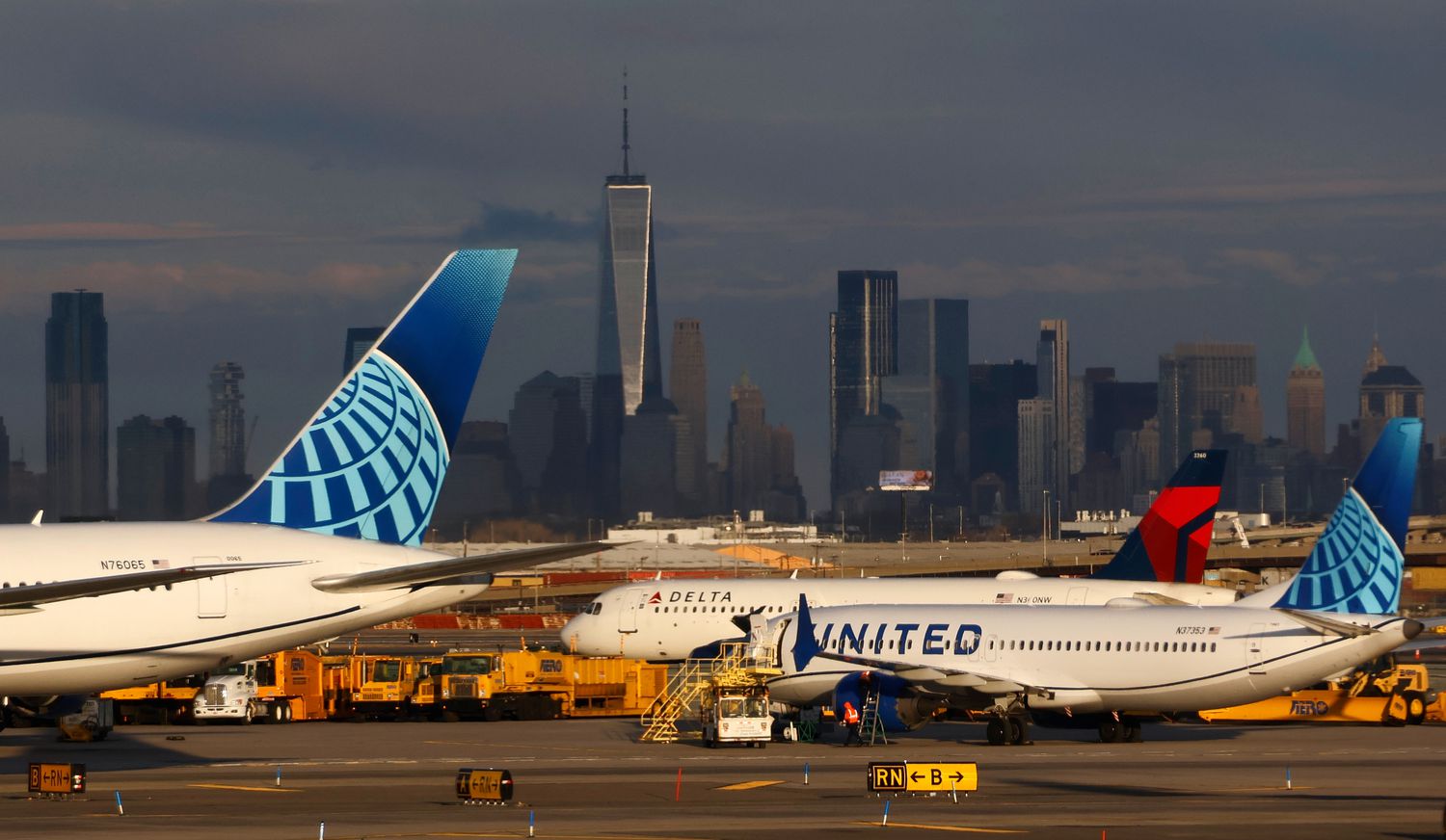 Planes from United and Delta Air Lines are seen on a runway, with the New York City skyline in the background.