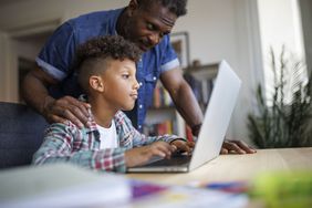 A child and an adult looking at a laptop screen at a table